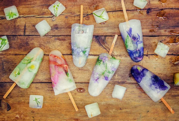 frozen flowers in ice cubes and ice cream on a stick. selective focus.