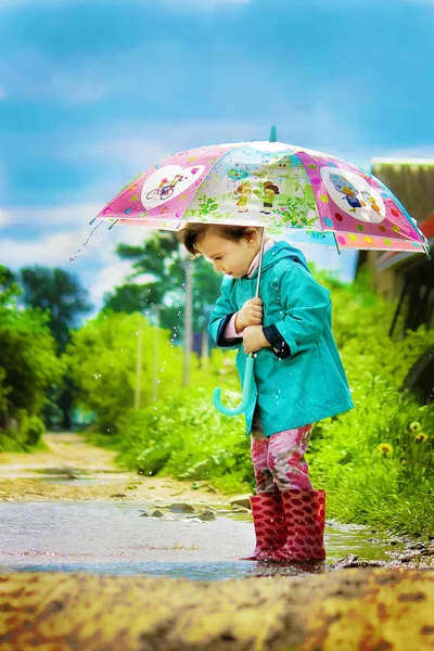 The child is in the rain. With an umbrella. Selective focus. — Stock Photo, Image
