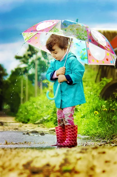 The child is in the rain. With an umbrella. Selective focus. — Stock Photo, Image