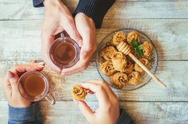 Eller erkek ve kadın ile bir fincan çay ve baklava. Seçici odak. 