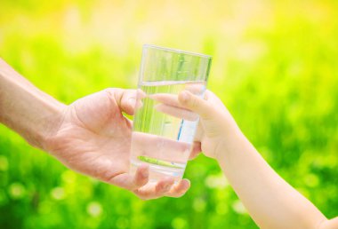 Baba çocuk bir bardak su verir. Seçici odak.