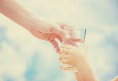 Baba çocuk bir bardak su verir. Seçici odak.