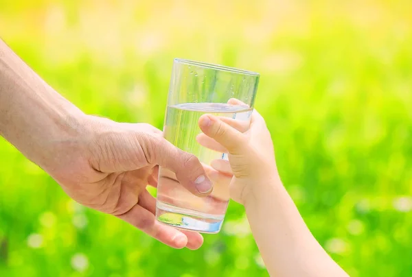 De vader geeft het kind een glas water. Selectieve aandacht. — Stockfoto