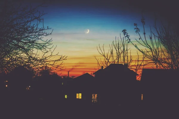 Abendhaus im Schatten und der junge Monat. — Stockfoto