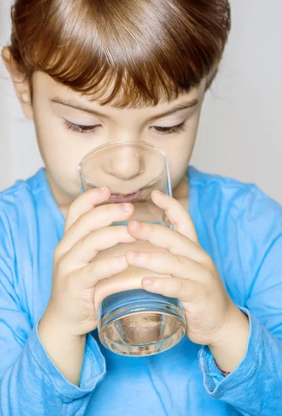 Bir çocuk bir bardak su tutuyor. Seçici odak. 