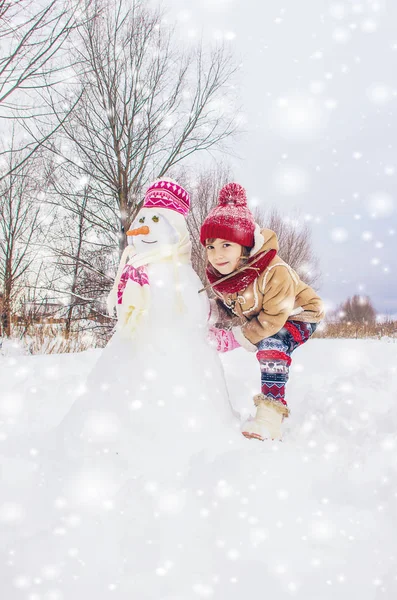Kış çocuk içinde belgili tanımlık kar. Bir kardan adam yapmak için. Seçici odak.