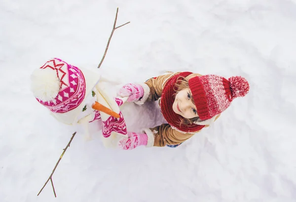 冬天的孩子在雪地里 做一个雪人 选择性焦点 — 图库照片