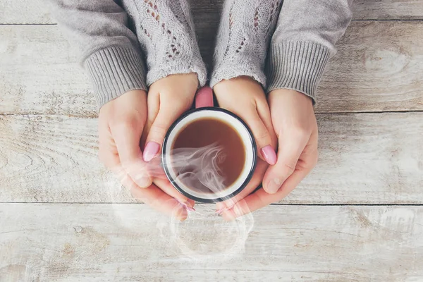 A cup of tea in the hands of a man and a woman. Selective focus.
