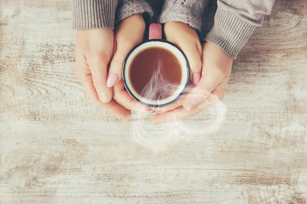 A cup of tea in the hands of a man and a woman. Selective focus.