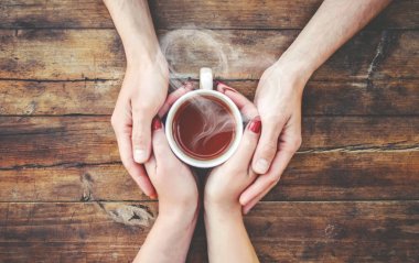 Bir fincan çay bir erkek ve bir kadın elinde. Seçici odak.