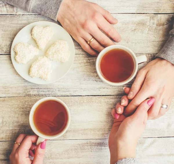 A cup of tea in the hands of a man and a woman. Selective focus.