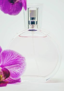 Bir şişe parfüm ve bir orkide çiçeği. Seçici odak.