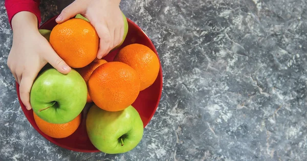 apples and oranges in the hands of a child. Selective focus.