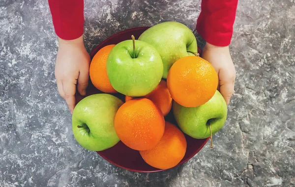 apples and oranges in the hands of a child. Selective focus.