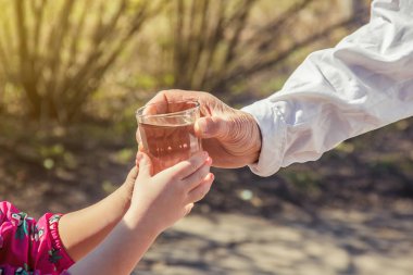 Büyükannem bir çocuğa bir bardak temiz su veriyor. Seçici odak. 