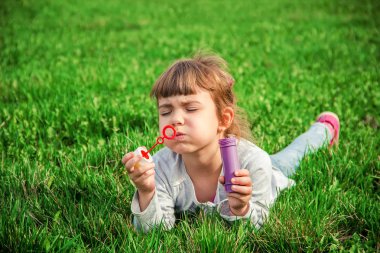 Bir çocuk yaz çimenlerin üzerinde yer almaktadır. Seçici odak.
