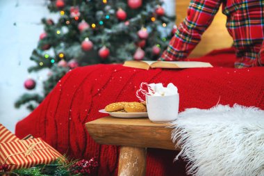 Noel sabahı, pijamalı bir kız bir fincan kremalı sıcak kakao ile. Seçici odak.