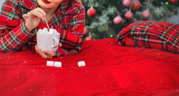 Mañana de Navidad, niña en pijama con una taza de cacao caliente con malvaviscos. Enfoque selectivo . — Foto de Stock