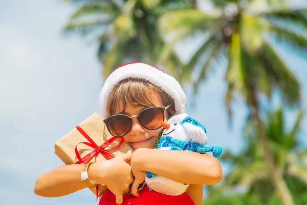 Uma criança à imagem do Pai Natal na praia. Foco seletivo . — Fotografia de Stock