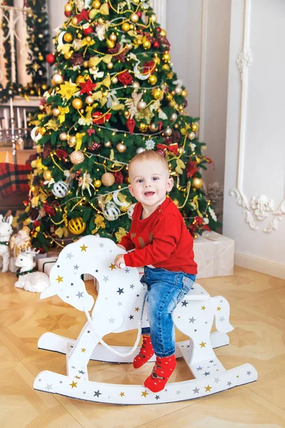 Un niño en un caballo de madera cerca del árbol de Navidad. Enfoque selectivo . — Foto de Stock