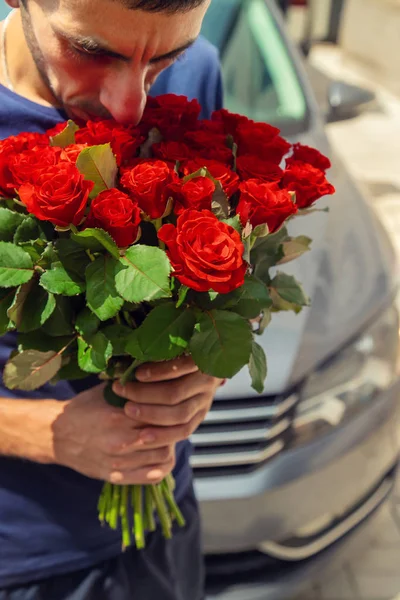 Egy csokor vörös rózsa egy férfi kezében. Szelektív fókusz. — Stock Fotó