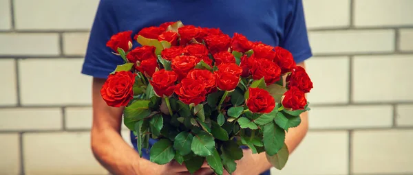 Un bouquet de roses rouges dans les mains d'un homme. Concentration sélective . — Photo