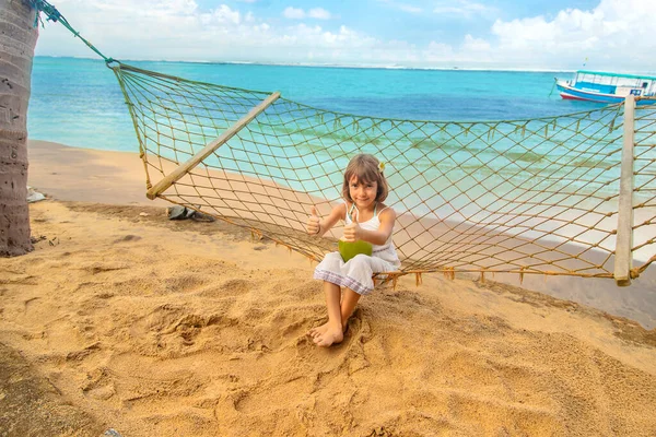 Дитяча дівчина п'є кокос на пляжі. Вибірковий фокус . — стокове фото