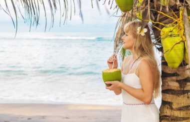 Sahildeki kız hindistan cevizi içiyor. Seçici odak.