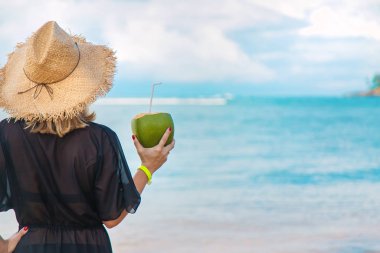 Sahildeki kız hindistan cevizi içiyor. Seçici odak.