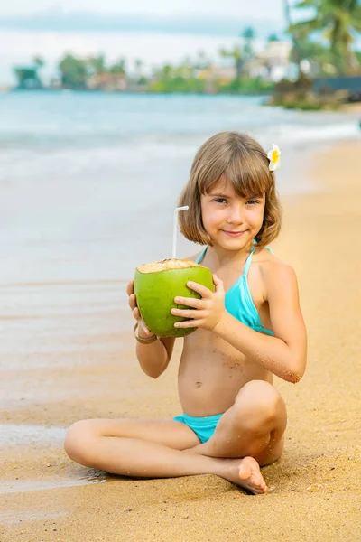 A child on the beach drinks coconut. Selective focus. — Stock Photo, Image