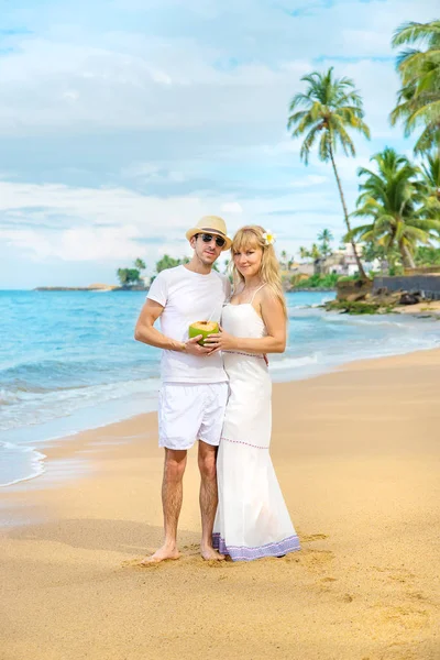 Um homem e uma rapariga na praia estão a beber coco. Foco seletivo . — Fotografia de Stock