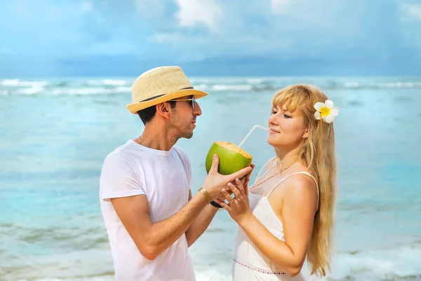 A man and a girl on the beach are drinking coconut. Selective focus. — Stock Photo, Image