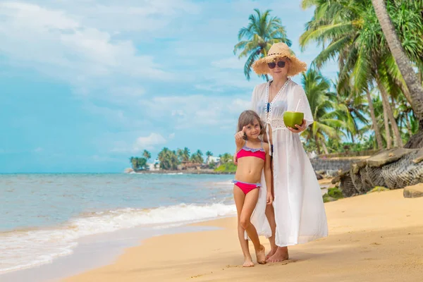 Mãe e filha bebem coco na praia. Foco seletivo . — Fotografia de Stock