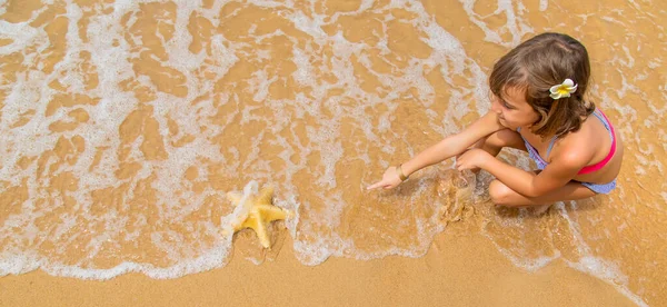 Dziecko z rozgwiazdy w rękach na plaży. Skupienie selektywne. — Zdjęcie stockowe