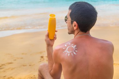 Sahilde sırtında güneş kremi olan bir adam. Seçici odak.