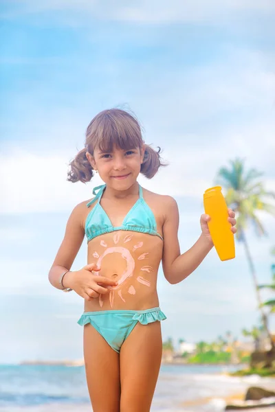 Child on the beach with sunscreen on his back. Selective focus. — Stock Photo, Image