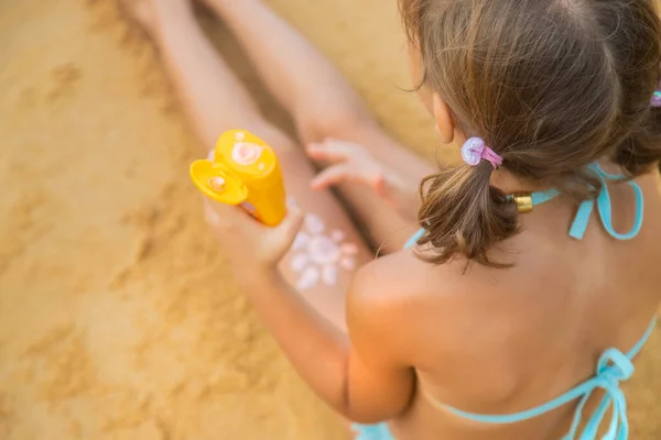 Ребенок на пляже с солнцезащитным кремом на спине. Селективный фокус. — стоковое фото
