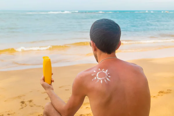 Человек на пляже с солнцезащитным кремом на спине. Селективный фокус . — стоковое фото
