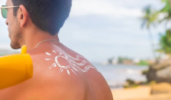 Человек на пляже с солнцезащитным кремом на спине. Селективный фокус . — стоковое фото