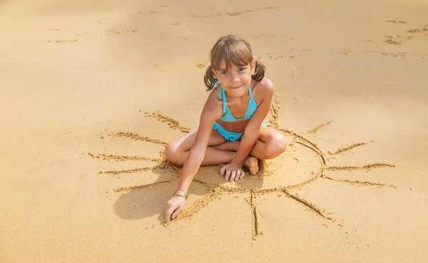 Dziecko rysuje słońce na plaży. Skupienie selektywne. — Zdjęcie stockowe