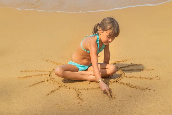 A child draws a sun on the beach. Selective focus. — Stock Photo, Image