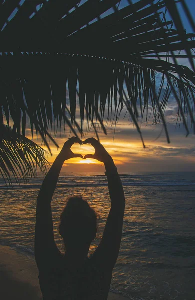 A rapariga faz mãos de coração ao pôr-do-sol. Sri Lanka. Foco seletivo . — Fotografia de Stock