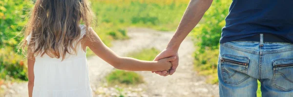 Padre e figlia camminano tenendosi per mano. Focus selettivo . — Foto Stock