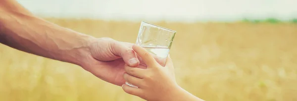 El padre le da al niño agua en el fondo del campo. Enfoque selectivo . — Foto de Stock