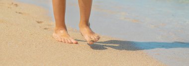 çocuk kumda ayak izleri bırakarak plaj boyunca yürür. Seçici odak. Doğa.