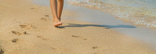 子供は砂の中に足跡を残してビーチに沿って歩きます 選択的な焦点 — ストック写真