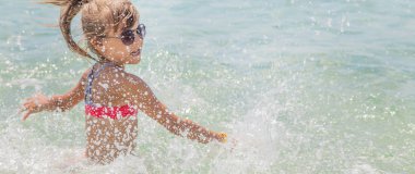 çocuk denize sprey yapar. Seçici odaklama.