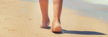 çocuk kumda ayak izleri bırakarak plaj boyunca yürür. Seçici odak. Doğa.