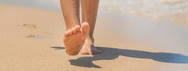子供は砂の中に足跡を残してビーチに沿って歩きます 選択的な焦点 — ストック写真