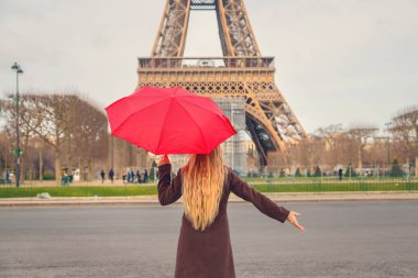 Paris 'teki Eyfel Kulesi yakınlarında kırmızı şemsiyeli bir kız. Seçici odaklanma. Doğa.